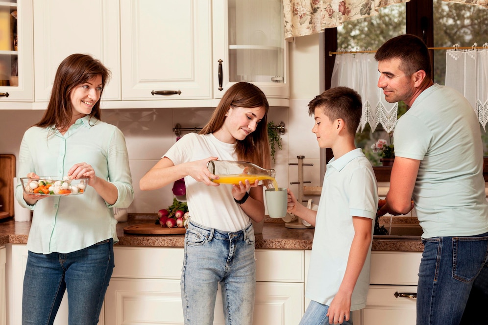 A family gathers in a kitchen, preparing food together with ingredients on the counter, fostering a warm atmosphere of collaboration.